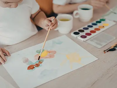 Criança desenvolvendo criatividade ao pintar com aquarela