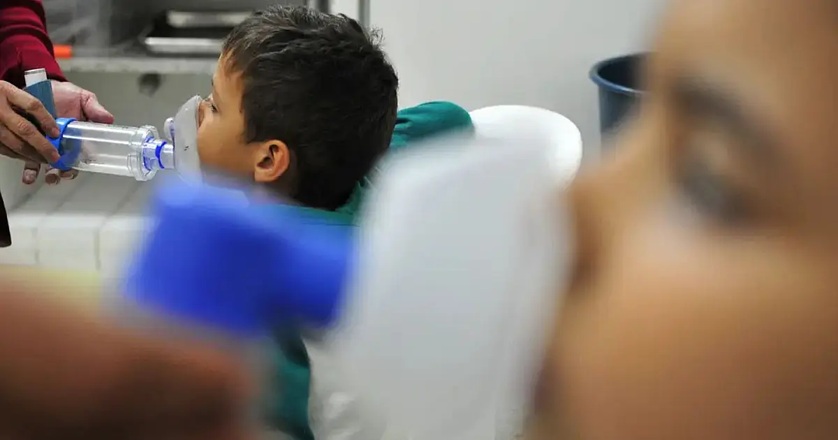 Profissional de saúde em unidade hospitalar durante atendimento de pacientes com síndrome respiratória.