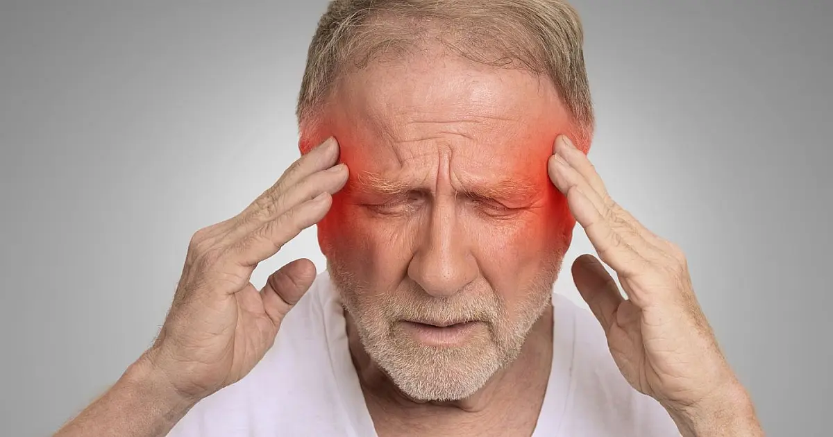 Homem idoso com dor de cabeça ao acordar segurando a cabeça