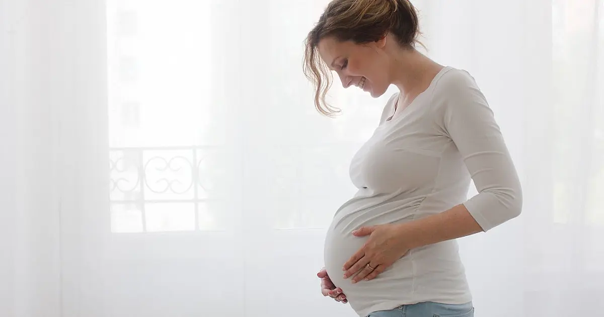Mulher grávida segurando a barriga durante sintomas de enjoo na gestação.