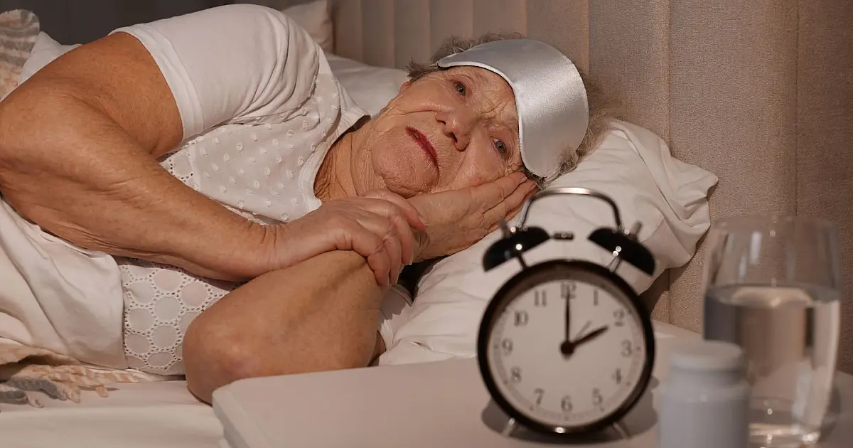 Idosa deitada na cama enfrentando dificuldade para dormir durante a noite