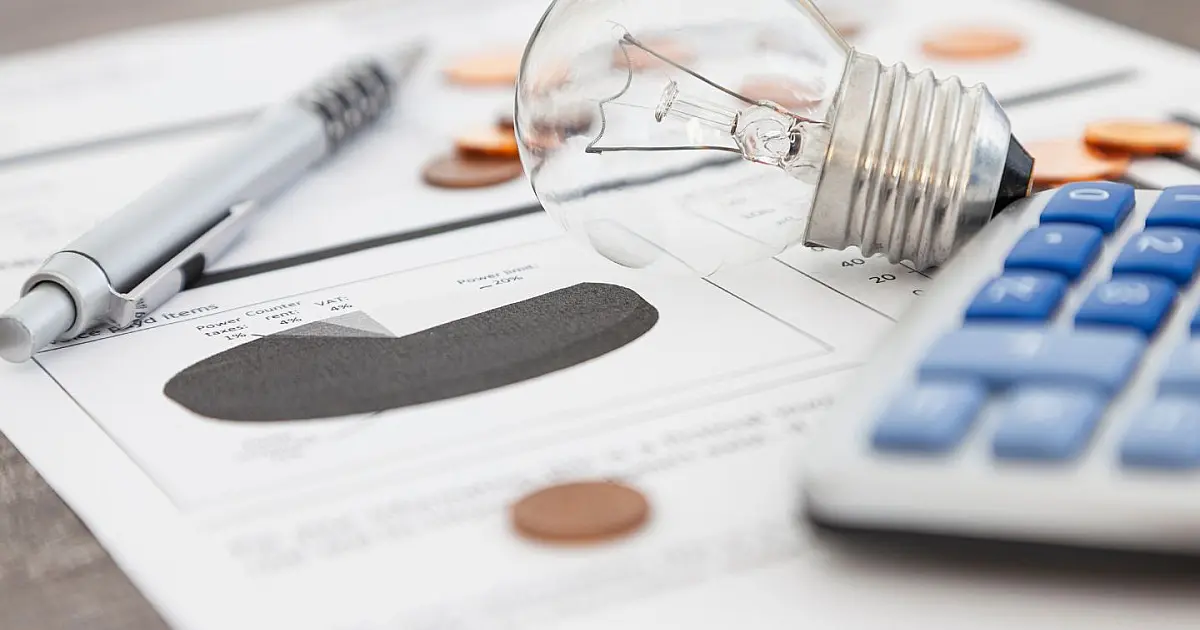 Lâmpada acesa sobre conta de energia elétrica simbolizando desconto na tarifa.