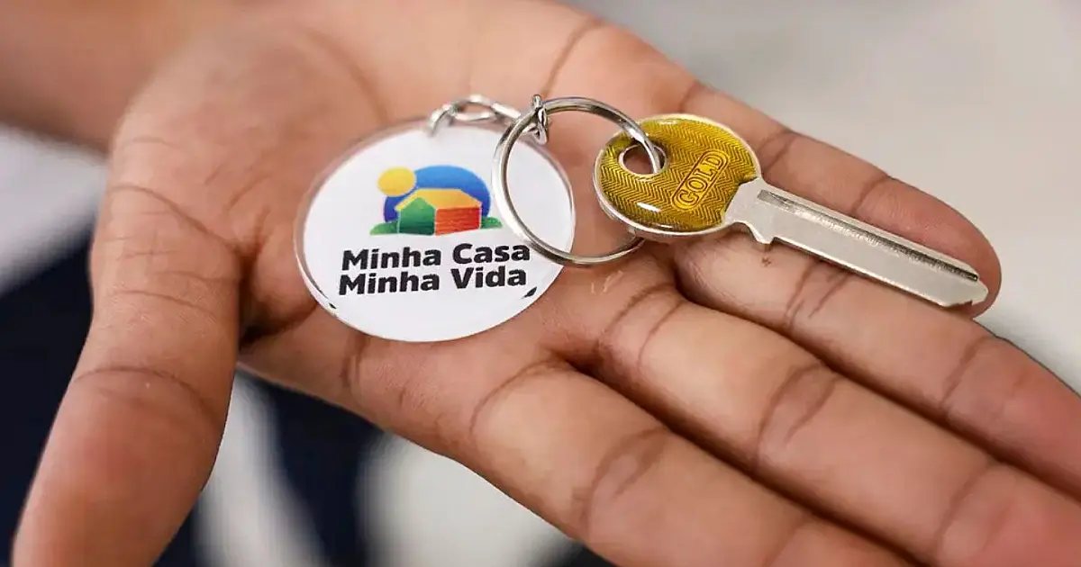 Pessoa segura chave com chaveiro do programa Minha Casa Minha Vida.