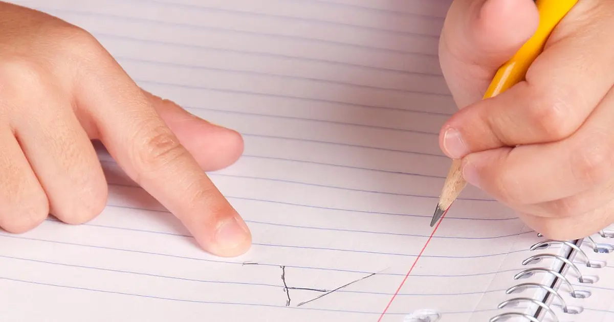 Criança aprendendo a escrever em atividade escolar em sala de aula