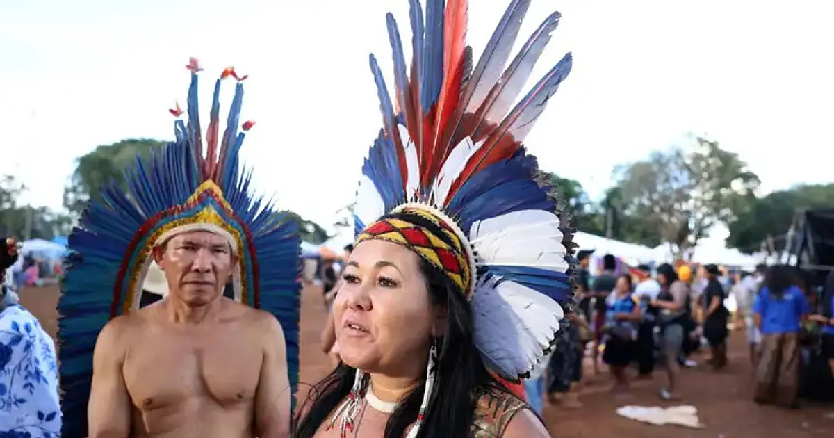 Artesã indígena produzindo cocar com penas naturais