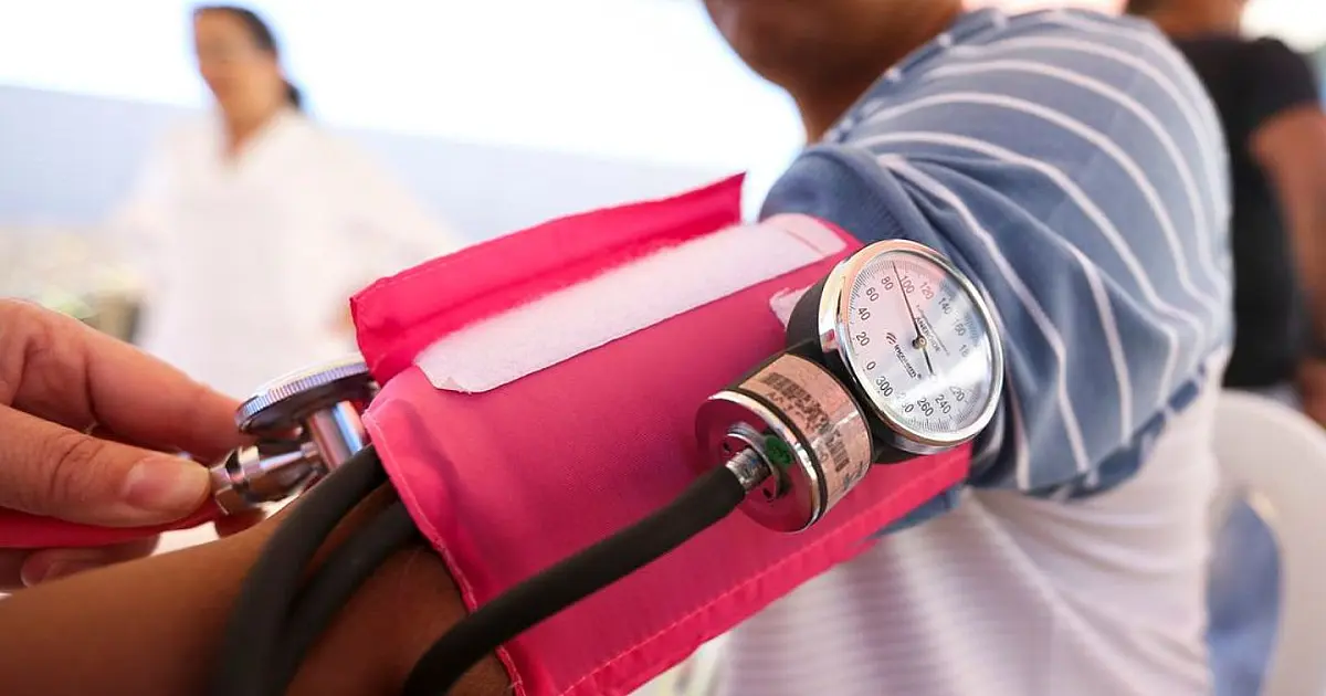 Pessoa aferindo pressão arterial durante atendimento de saúde.