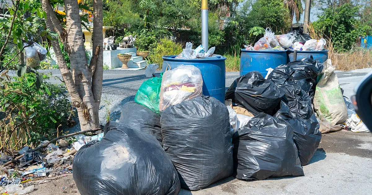 Sacos de lixo descartados em calçada representando multa para quem jogar lixo na rua.
