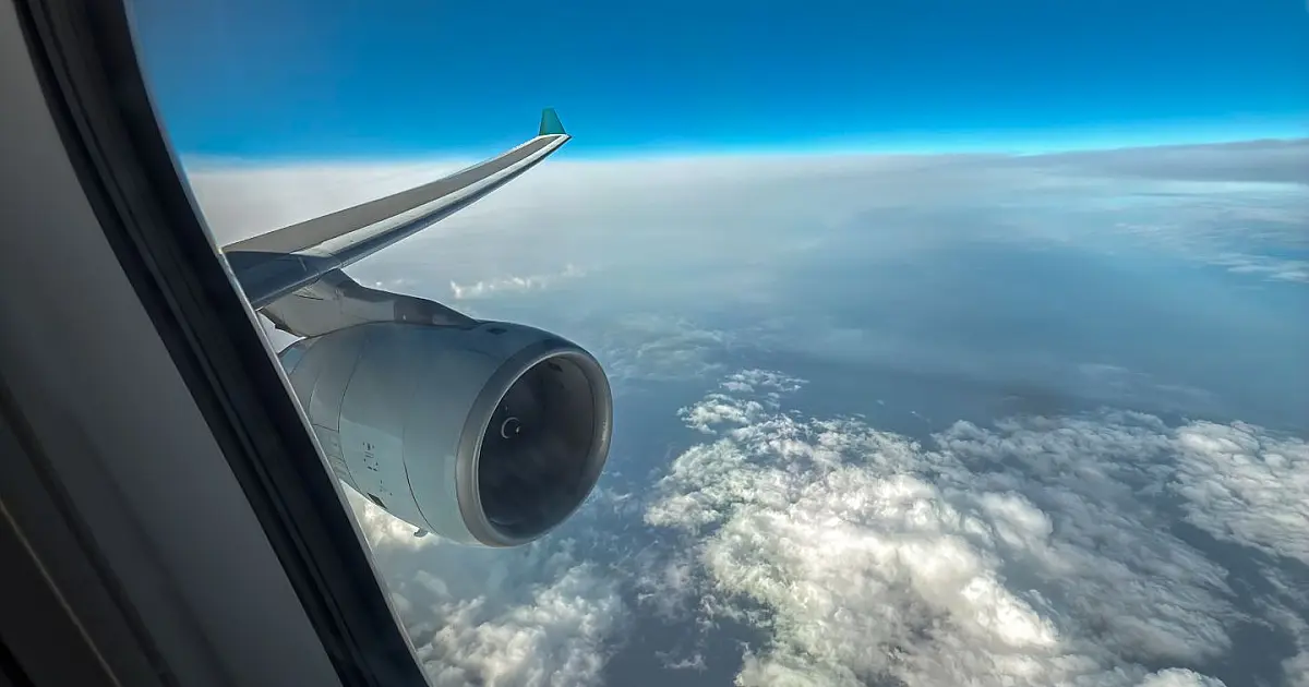 Asa de avião vista da janela durante voo acima das nuvens.