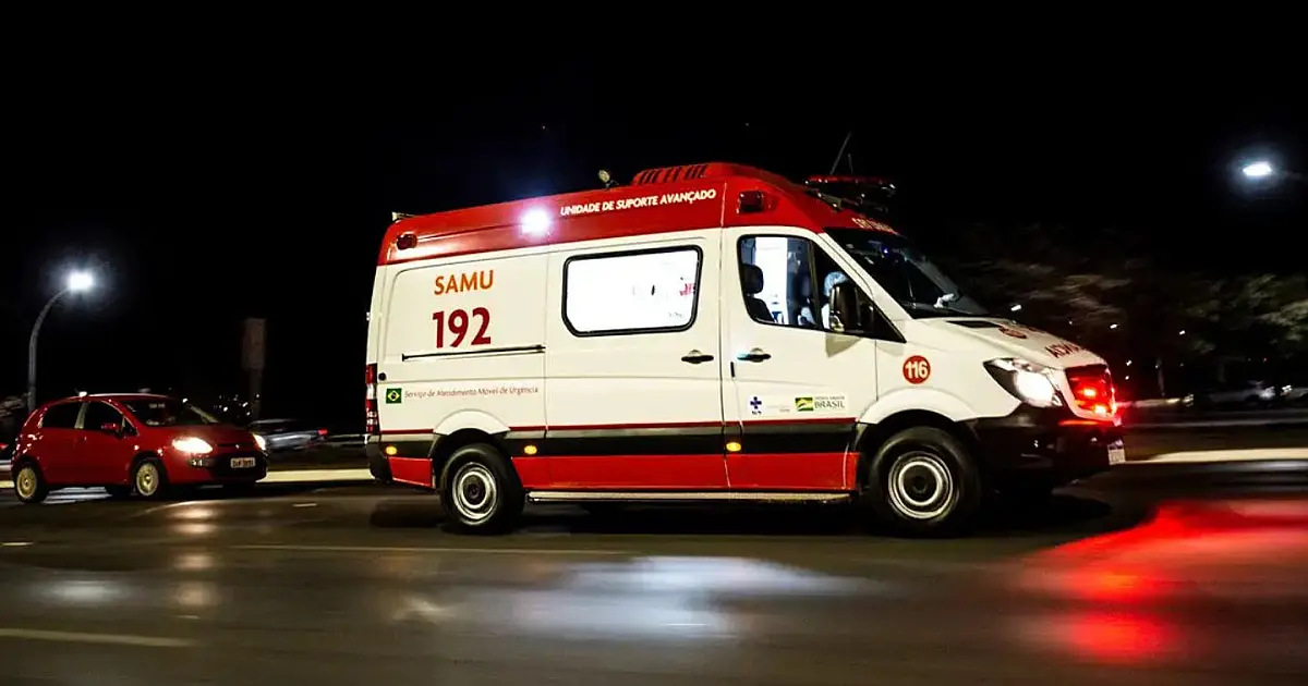 Ambulância branca de suporte avançado estacionada com as portas traseiras abertas e luzes de sinalização apagadas.