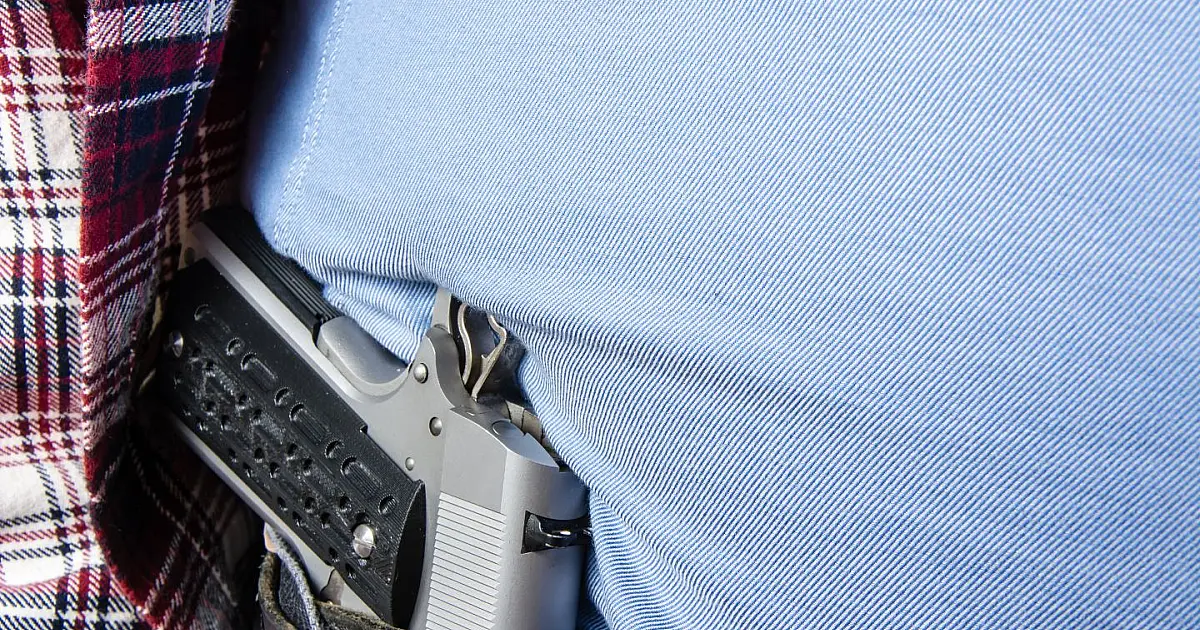 Pessoa segurando arma de forma discreta representando debate sobre porte de arma no Brasil