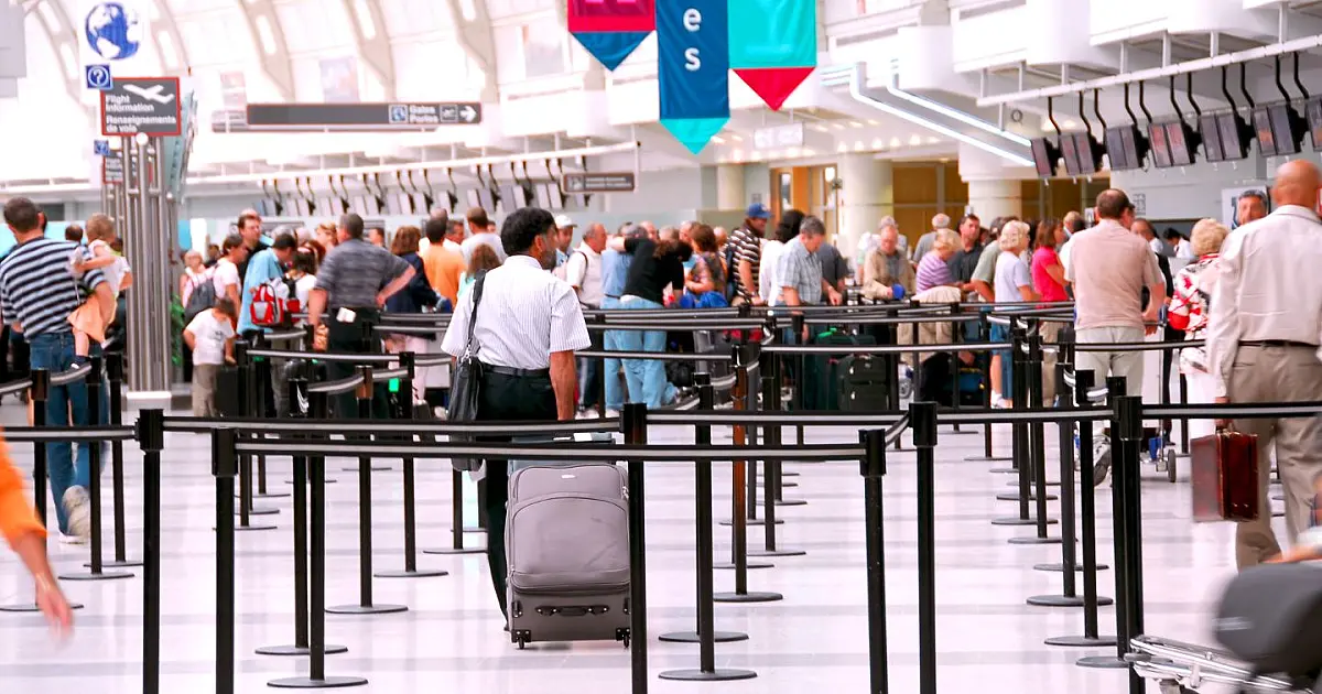 Movimentação intensa de passageiros em aeroporto durante cancelamentos de voos internacionais.