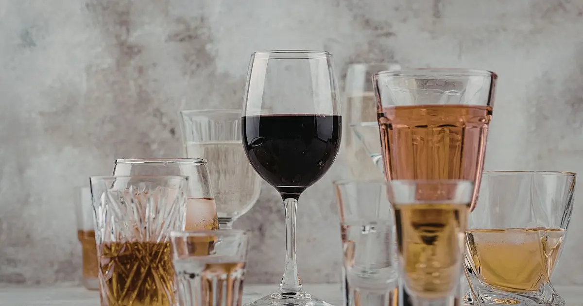 Copos com diferentes bebidas alcoólicas sobre superfície texturizada representando destilados fortes e variados