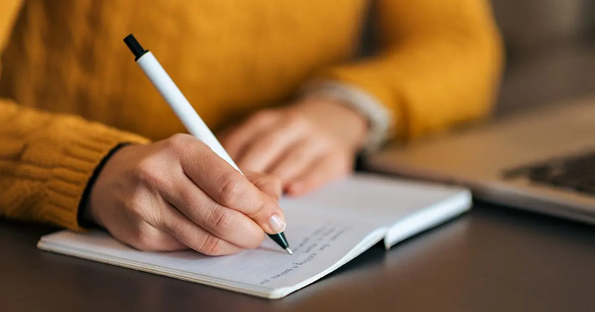 Pessoa escrevendo em caderno durante atividade de estudo ou aprendizado.