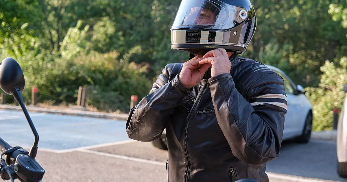 Motociclista colocando capacete antes de subir em motocicleta.