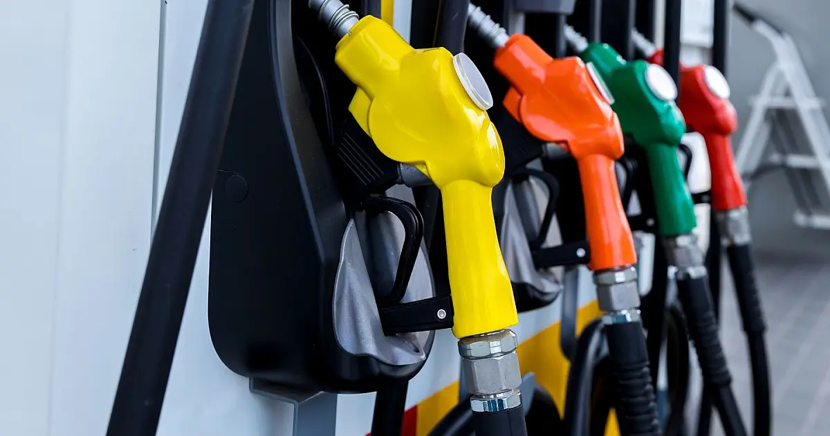 Close-up focado em bicos de abastecimento de combustível coloridos e alinhados em uma bomba de posto de gasolina moderno.