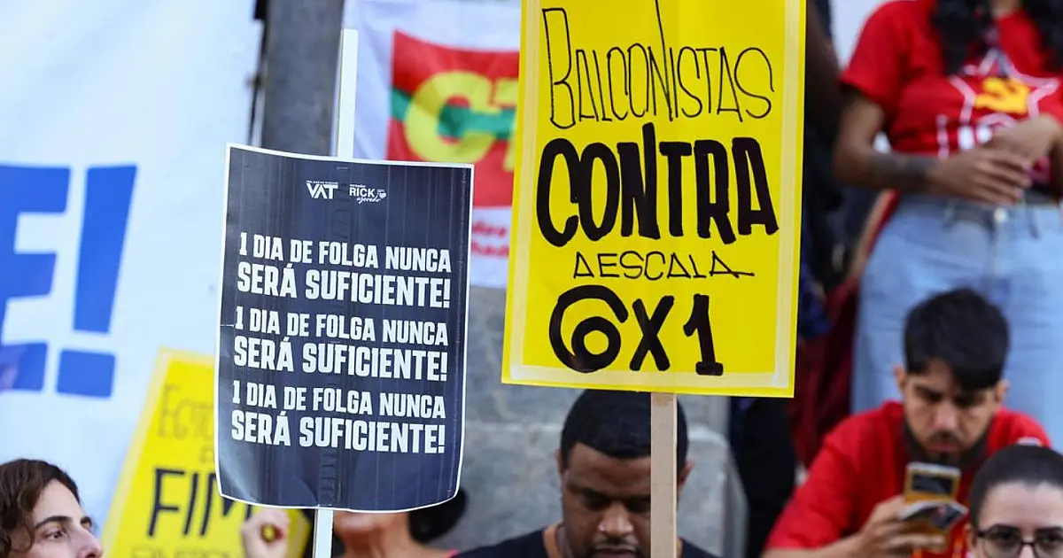 Deputados sentados em torno de uma grande mesa de reuniões em plenário de comissão, com microfones e painéis eletrônicos ao fundo.