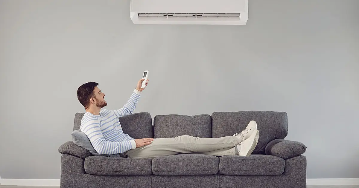 Homem utilizando ar-condicionado em sala climatizada durante período de calor