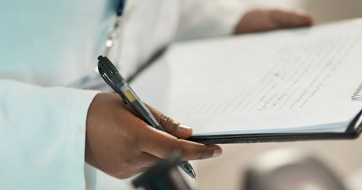Profissional analisando documentos médicos durante prova prática do Revalida 2025.