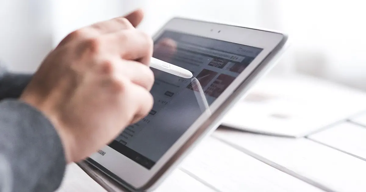 Pessoa utilizando tablet representa investigação sobre perfil falso do INSS nas redes sociais