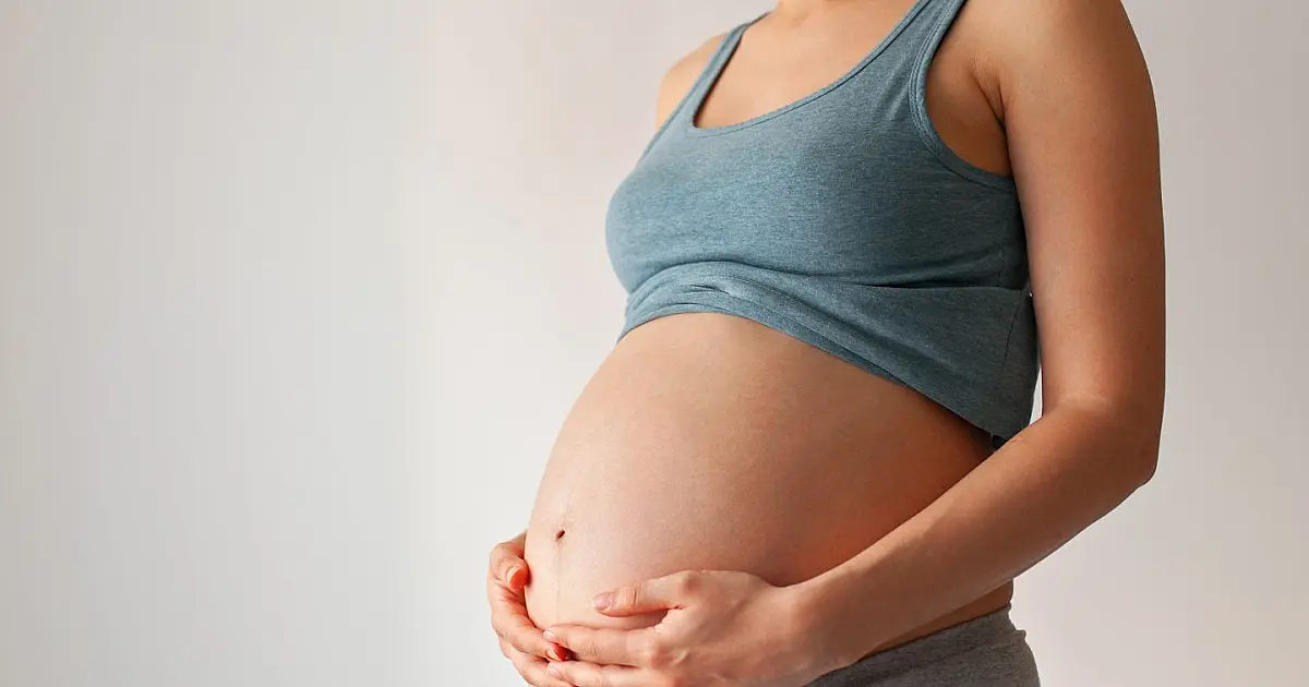 Mulher grávida segurando barriga durante período de gestação