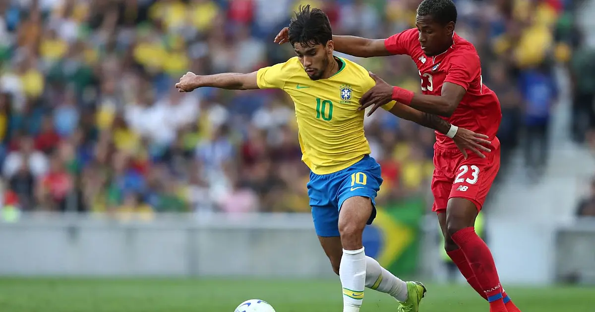 O meio-campista Lucas Paquetá, vestindo o uniforme da Seleção Brasileira, disputa a posse de bola de forma intensa com um defensor da seleção do Panamá no gramado do Estádio do Dragão.