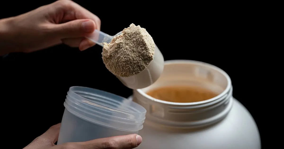 Pessoa segurando medidor de Whey Protein durante preparo de suplemento alimentar relacionado à sustentabilidade.