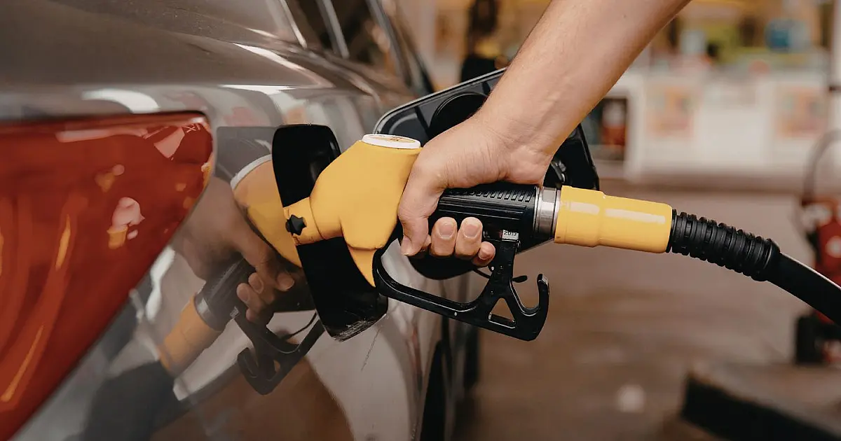Pessoa abastecendo veículo em posto de combustíveis durante aumento dos preços da gasolina.