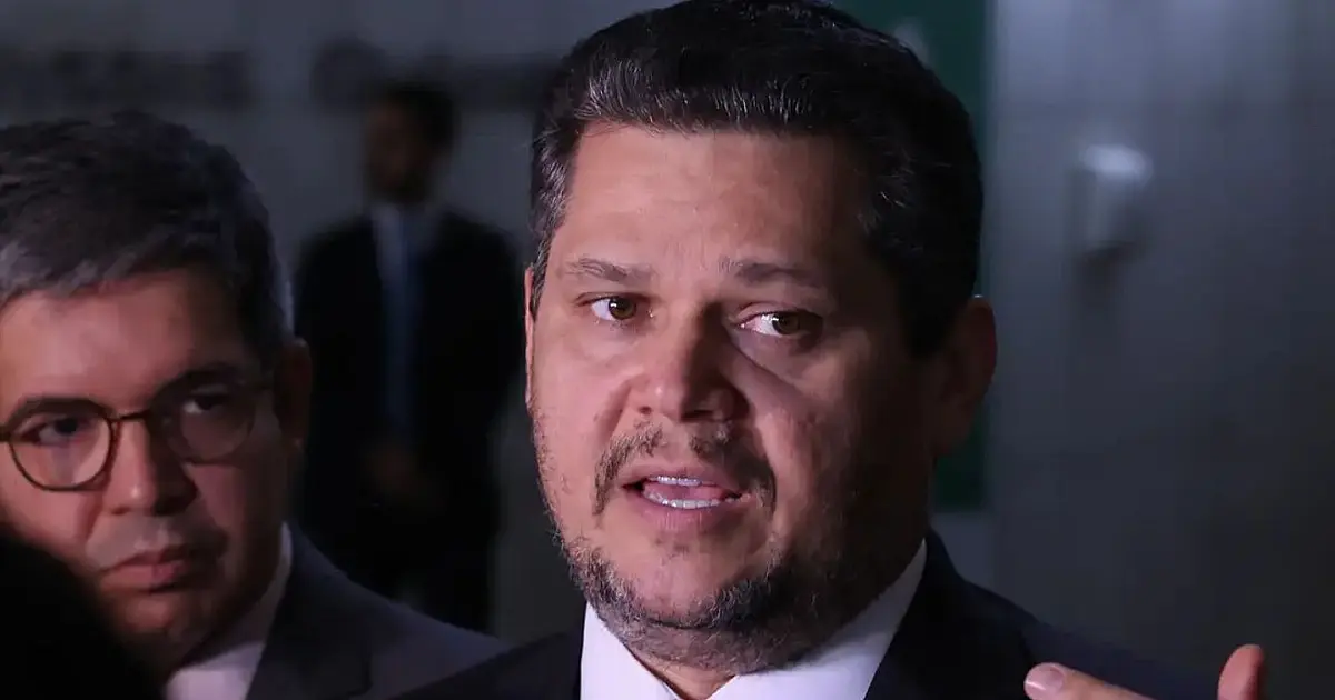 O senador Davi Alcolumbre falando ao microfone no plenário do Senado, vestindo terno escuro e gravata, com as bandeiras oficiais ao fundo