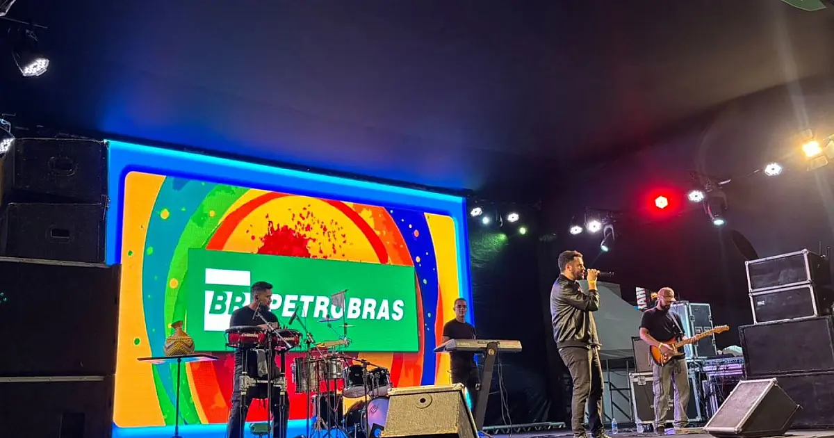 Vista interna da Pirâmide do Parque do Povo iluminada, com trios de forró tocando sanfona e triângulo no centro do tablado enquanto o público acompanha ao redor