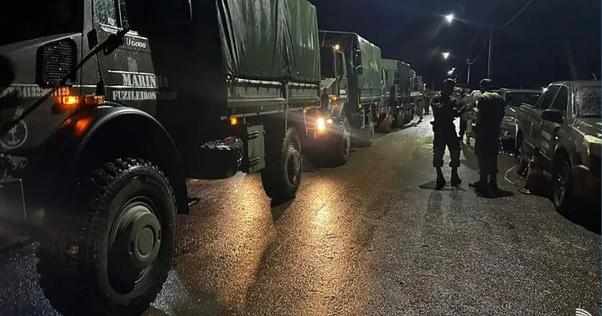Militares da Marinha do Brasil e da FAB organizando paletes de caixas de medicamentos e equipamentos médicos ao lado de uma aeronave cargueira cinza em uma pista de pouso