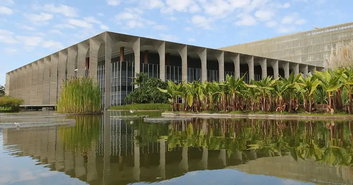 Fachada externa do Palácio do Itamaraty com seus arcos tradicionais refletidos no espelho de água em Brasília