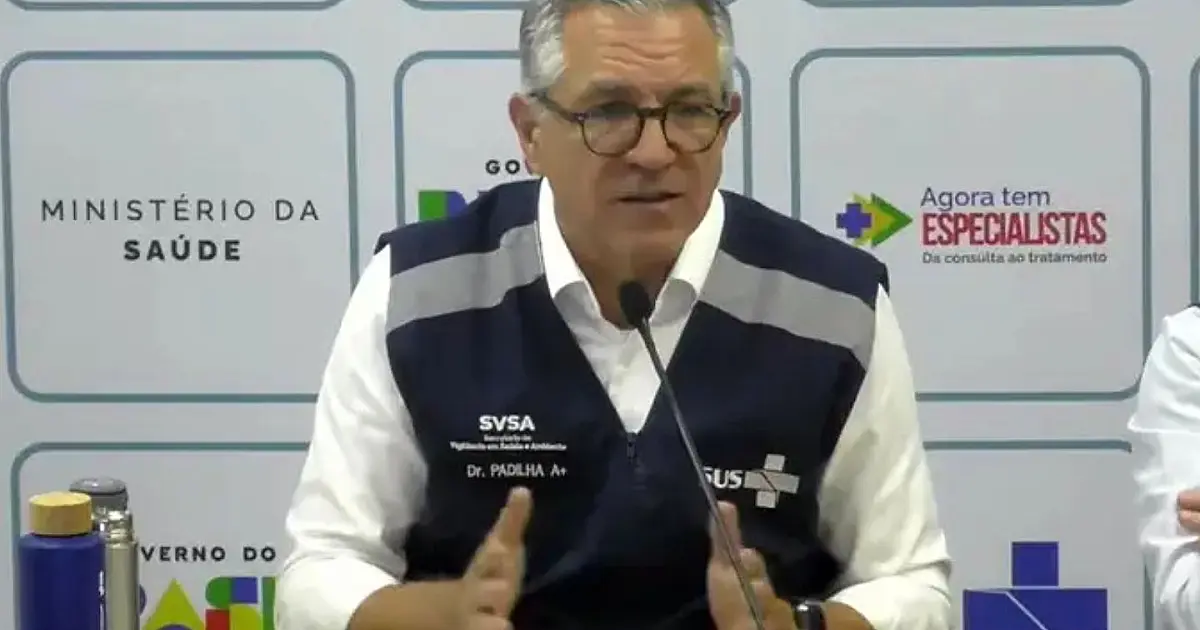 Ministro da Saúde Alexandre Padilha falando ao microfone durante pronunciamento oficial em coletiva de imprensa com painel institucional ao fundo