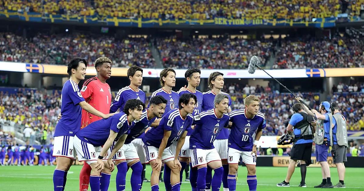 Jogadores da seleção do Japão vestindo o uniforme azul tradicional, correndo e se abraçando no centro do gramado em comemoração ao término da partida