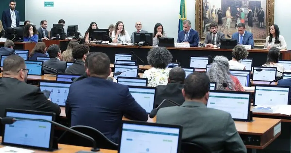 Deputados sentados em bancadas semicirculares de um comitê do Congresso Nacional debatendo com microfones e telas eletrônicas à frente