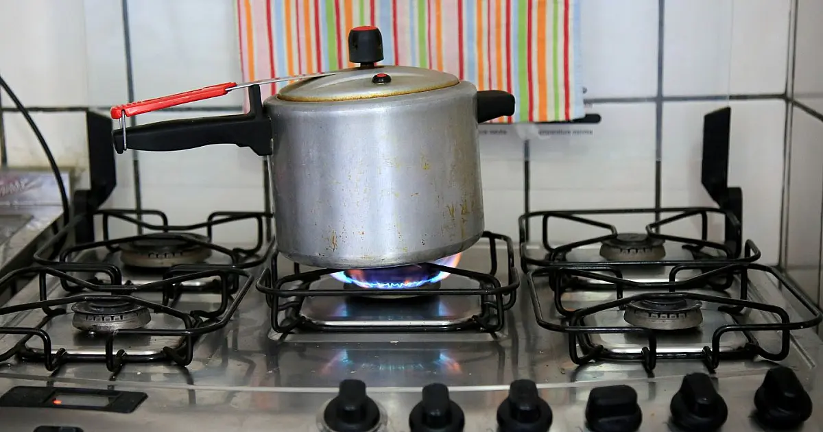 Panela de pressão eletrônica posicionada sobre a bancada de uma cozinha organizada e bem iluminada