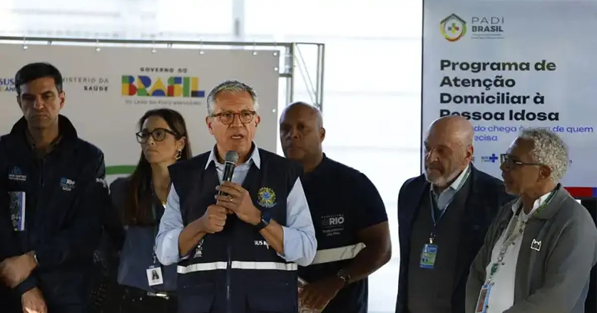 O ministro da Saúde, Alexandre Padilha, falando ao microfone em um púlpito iluminado durante o evento oficial de lançamento do programa de saúde no Rio de Janeiro.