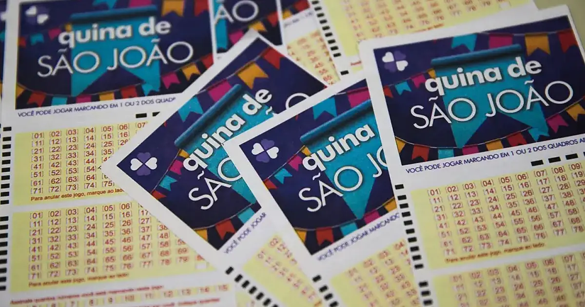 Vários canhotos e guias de jogos de loteria empilhados sobre uma mesa de madeira clara, com uma caneta preta ao lado em foco seletivo