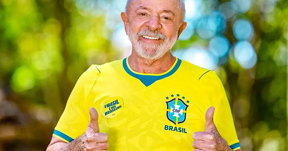 O presidente Lula sorrindo, vestindo a camisa oficial da Seleção Brasileira de futebol durante gravação em ambiente interno
