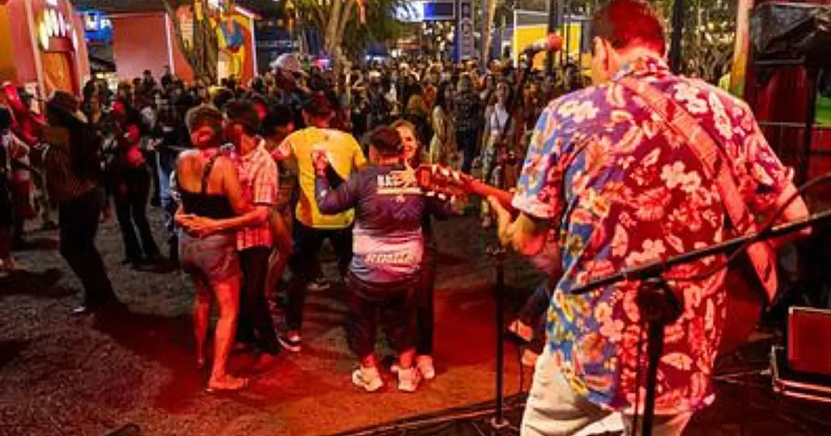 Casal dançando forró sorridente em uma palhoça decorada com balões coloridos e bandeirinhas de papel