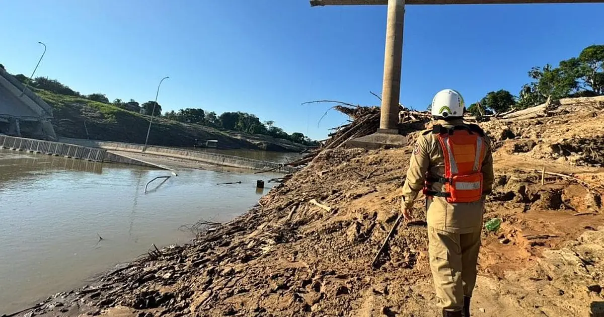 Agente do corpo de bombeiros com fardamento operacional observando os escombros retorcidos de uma grande estrutura de concreto
