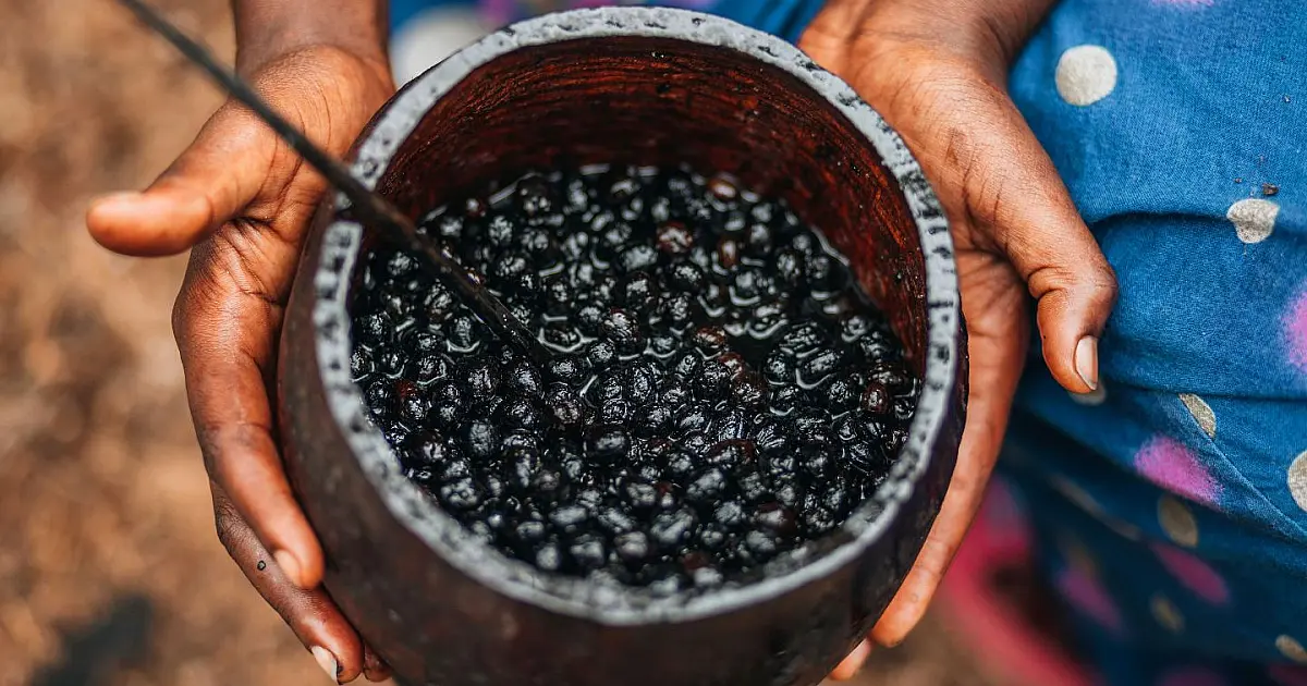 Texto alternativo: Tigela de cerâmica cheia de açaí roxo concentrado sobre uma mesa de madeira rústica