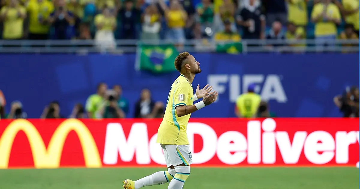 Neymar Jr. sorrindo e correndo pelo gramado do Hard Rock Stadium vestindo a camisa amarela número 10 da Seleção Brasileira durante partida oficial