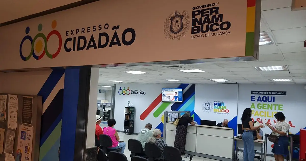 Mulher idosa centenária de cabelos brancos sorrindo gentilmente enquanto posa para a foto oficial de identificação em um guichê público