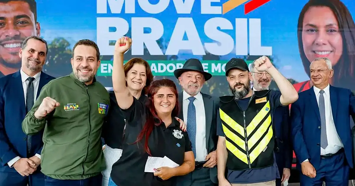 O presidente Lula discursando em um púlpito oficial no Palácio do Planalto ao lado de ministros e representantes de motociclistas de aplicativo